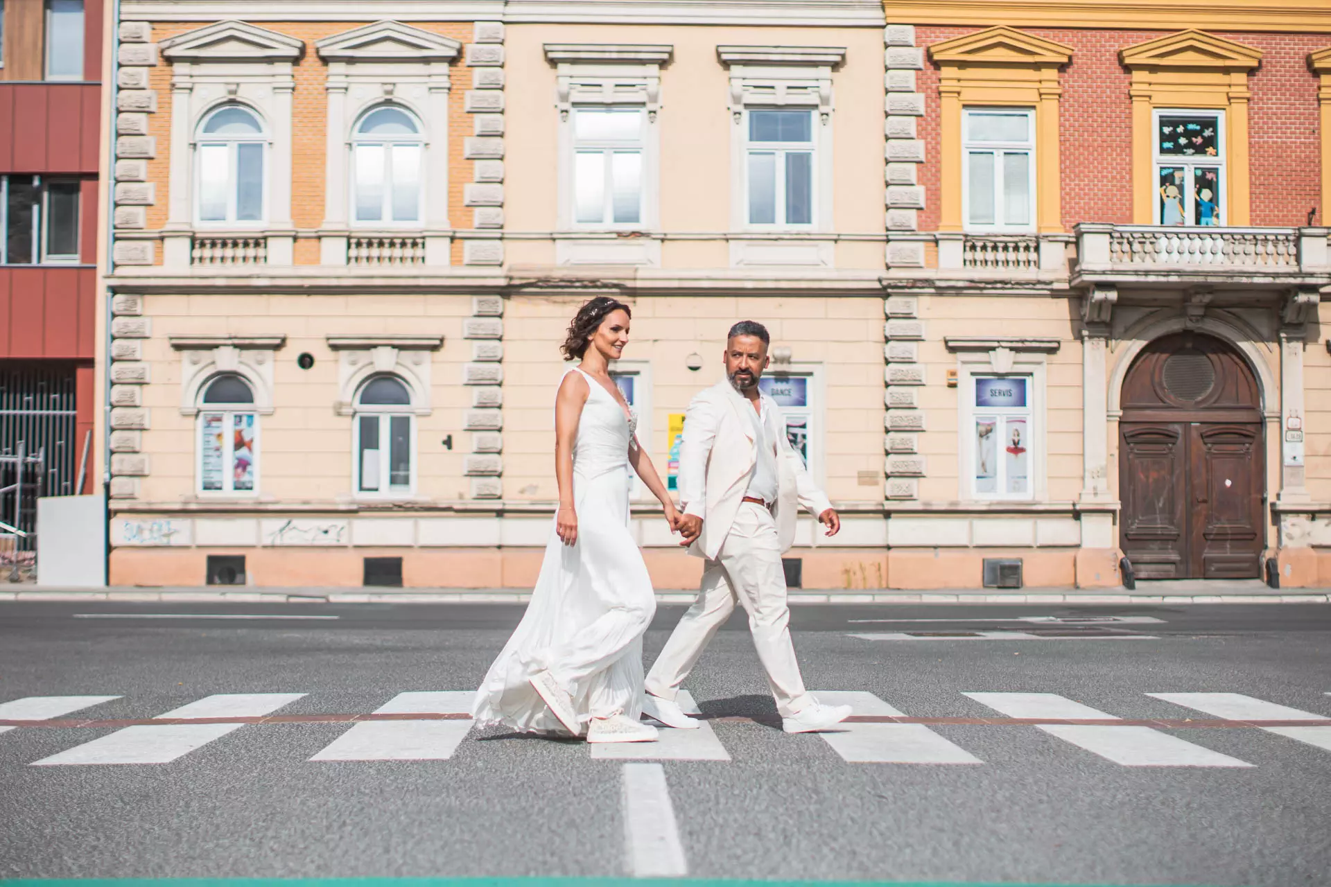 Svadobná fotka so ženíchom v bielom obleku v na ceste